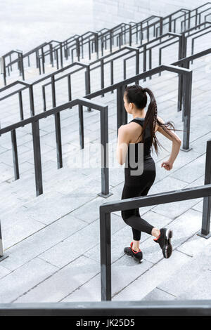 Young fitness woman in sportswear running down on stadium stairs Stock Photo