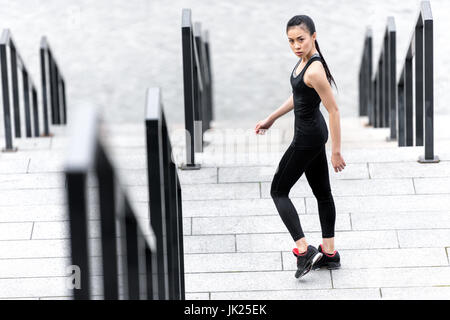 Athletic young woman in sportswear standing on stadium stairs and looking at camera Stock Photo