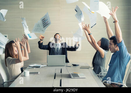 Celebrating success. Group of young business people throwing documents and looking happy while sitting at their working places in office Stock Photo