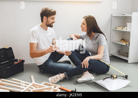 Young man and woman doing apartment repair together looking on plan Stock Photo