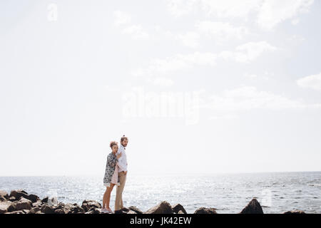 Middle Eastern couple standing on rocks near ocean Stock Photo