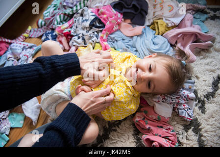 Hands of Caucasian mother tickling baby daughter on floor Stock Photo