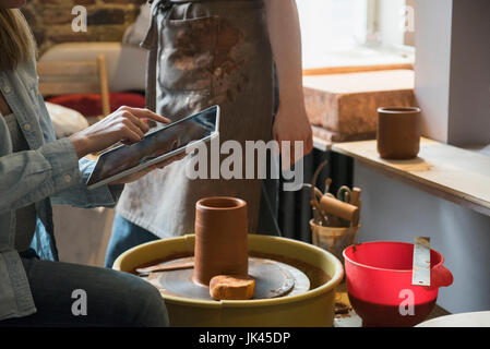 Caucasian women using digital tablet near pottery wheel Stock Photo
