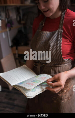 Caucasian woman examining drawings in book Stock Photo