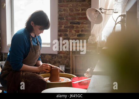 Caucasian woman shaping clay on pottery wheel Stock Photo