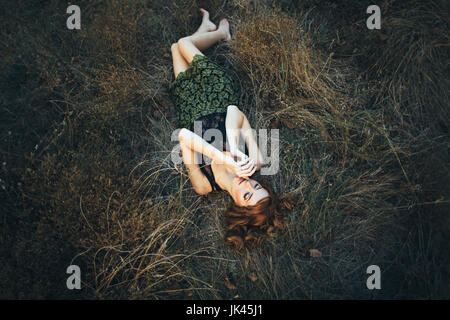 Pensive Caucasian woman laying on grass Stock Photo
