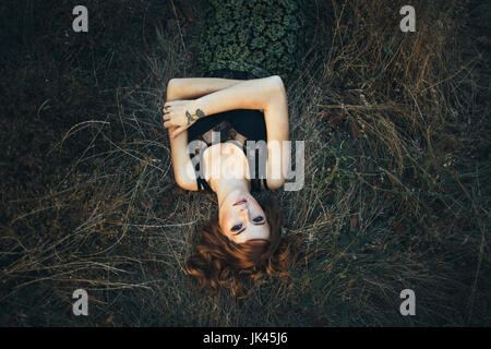 Serious Caucasian woman laying on grass Stock Photo