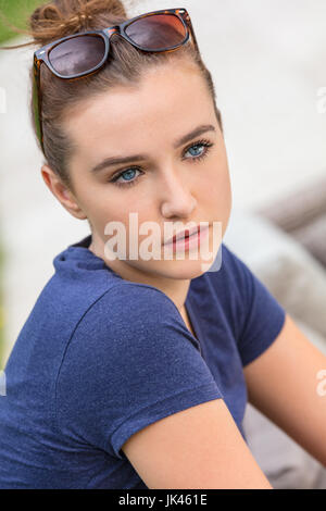 Pretty female teenager girl or young woman with blue eyes outside wearing sunglasses Stock Photo