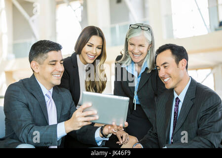 Smiling business people reading digital tablet in lobby Stock Photo