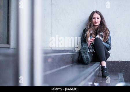 Pensive Caucasian woman sitting on staircase Stock Photo