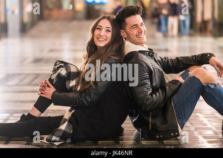 Caucasian couple sitting back to back on lobby floor Stock Photo