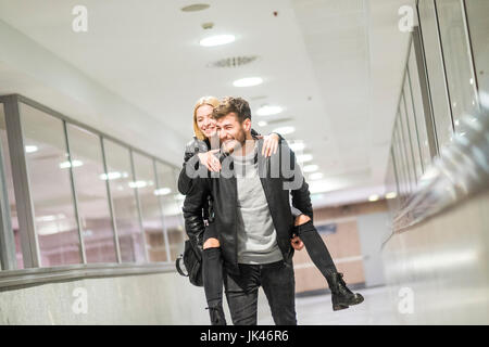 Caucasian man carrying woman piggyback in corridor Stock Photo