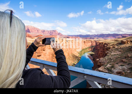 Caucasian woman photographing canyon river with cell phone Stock Photo