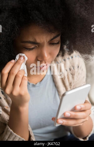 African American woman crying and texting on cell phone Stock Photo