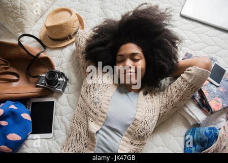 African American woman laying on bed anticipating travel Stock Photo