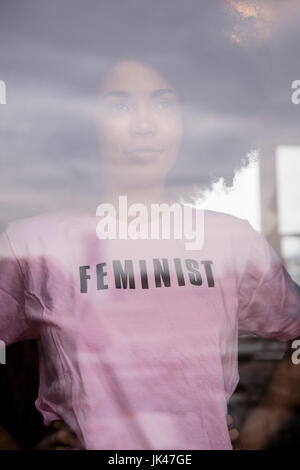 African American woman wearing feminist t-shirt behind window Stock Photo