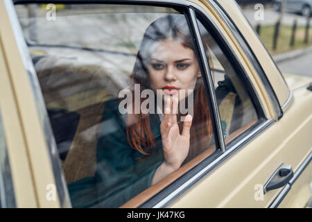 Pensive Caucasian woman in back seat of car leaning on window Stock Photo