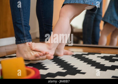 Reflection in mirror of barefoot Caucasian mother and daughter Stock Photo