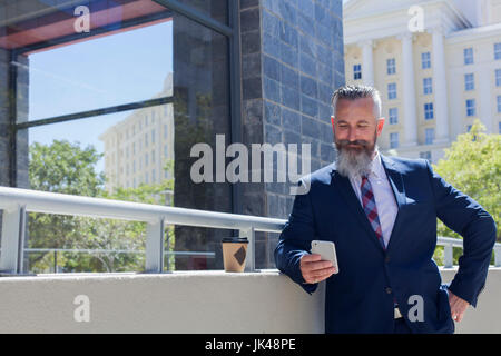 Caucasian businessman texting on cell phone outdoors Stock Photo