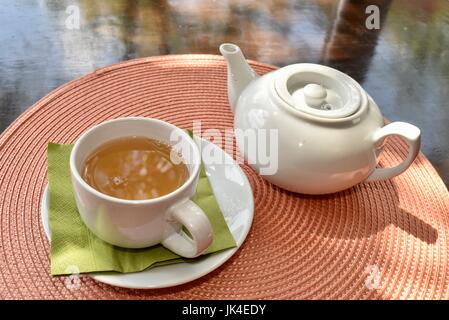 Tea service with pot and cup full of tea on a table at Tea Haus in Ann Arbor, Michigan, on sunny day. Stock Photo