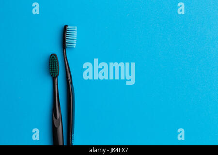 Two black toothbrushes on empty blue background, space for text Stock Photo