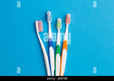 Photo of multi-colored toothbrushes on empty blue background Stock Photo
