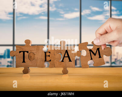 hand holding brown jigsaw pieces with team concept Stock Photo