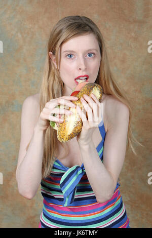 Young blonde girl eating large tasty sandwich Stock Photo