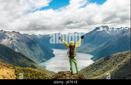 Hiker looking at the South Fiord of Lake Te Anau, stretching arms in the air, at back Southern Alps, at the Kepler Track Trail Stock Photo