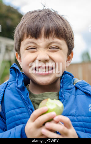 A boy eating a home grown apple in the back garden. Stock Photo