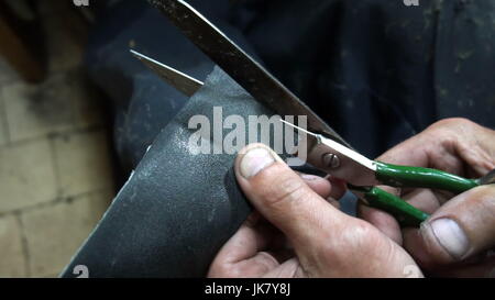 the shoemaker cuts out a patch for shoes. Stock Photo
