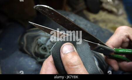 the shoemaker cuts out a patch for shoes. Stock Photo