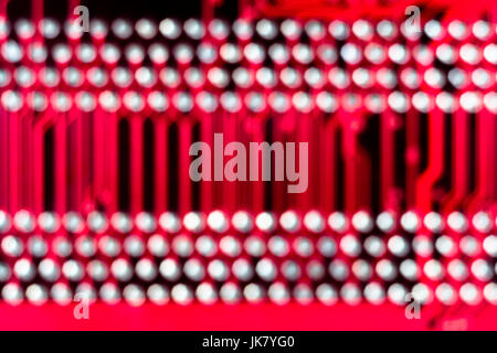 Abstract out of focus shot of the connector tracks on a red printed circuit board (pcb). Abstract dots. Stock Photo