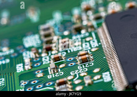 Surface mount technology (SMT) components on a green printed circuitboard. Wiring inside computer, circuit close up, detail of a circuit board. Stock Photo