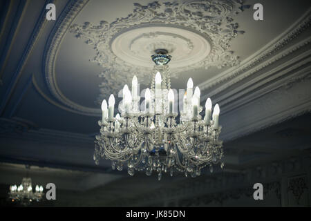 Beautiful antique crystal chandelier hangs from the ceiling in the shadows Stock Photo