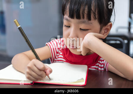 Asian Chinese little girl doing homework at outdoor cafe Stock Photo