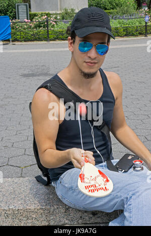 A young man in Union Square Park playing the old fashioned simple game, paddle ball. Stock Photo