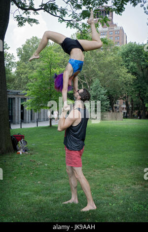 An athletic fit couple do acro yoga exercises in Washington Square Park in New York City. Stock Photo