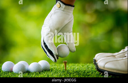 golf players hand placing ball on tee Stock Photo