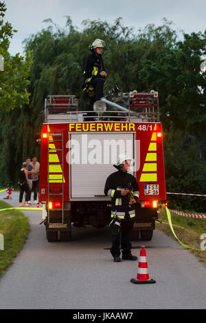German fire fighter at fire truck observing column of fire at solstice celebrations and midsummer festival Stock Photo