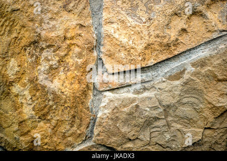 The background of cement and red blocks on a plain textured wall with cracks close-up . A horizontal frame. Stock Photo