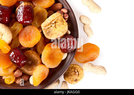 Dried fruits on a white background. Dates, lemon, apricots, figs and nuts in a clay plate. Stock Photo