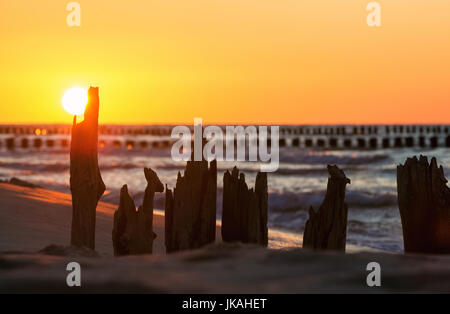 Sunset over the Baltic Sea against the background of old wooden breakwaters Stock Photo