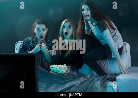 Teenage girls watching horror movie with popcorn Stock Photo