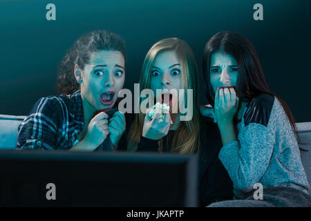 Teenage girls watching horror movie with popcorn Stock Photo