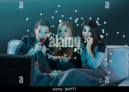 Teenage girls watching horror movie with popcorn Stock Photo