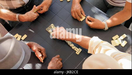 Retired people, seniors and free time. Old latino men having fun and playing game of domino in Cuba. High angle view. Stock Photo