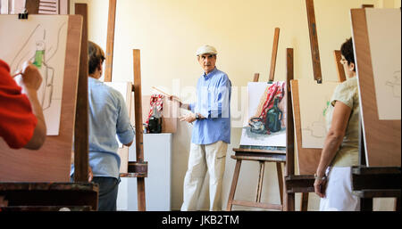 Elderly people painting for hobby. Group of active seniors at art school. Old man at work as teacher, teaching technique to students. Stock Photo