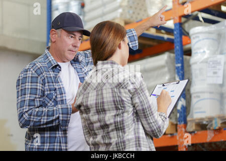 manager noting on clipboard and worker in warehouse Stock Photo