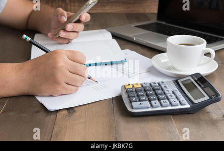 business woman writing and analyzing graphs on work table with computer and calculator Stock Photo